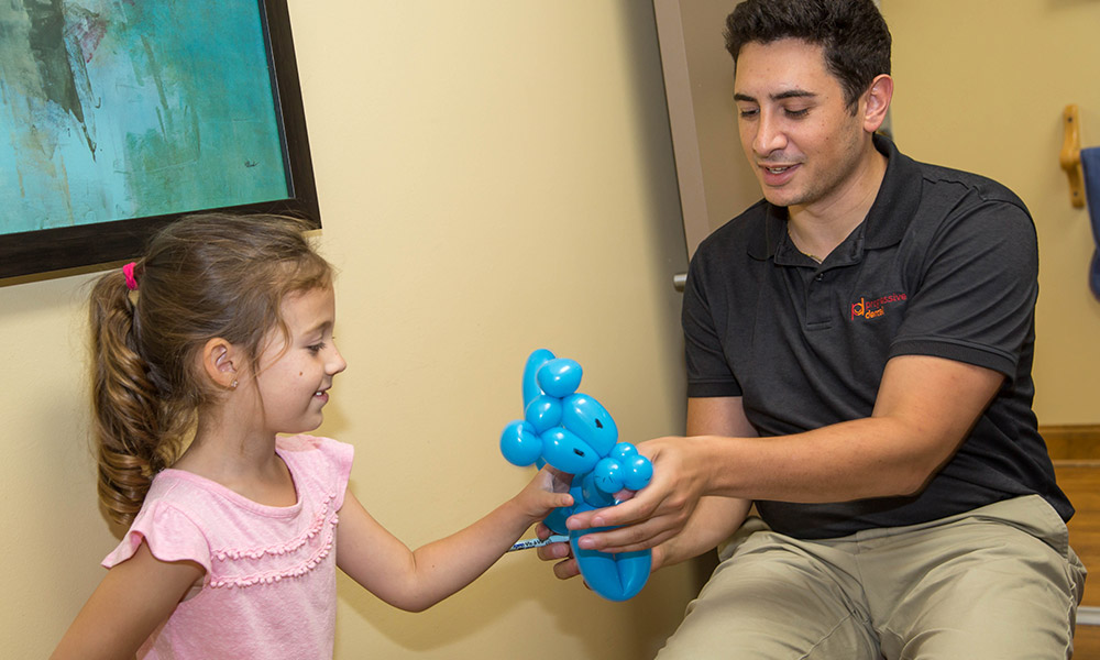 Dr. Spera giving a balloon animal to a young patient