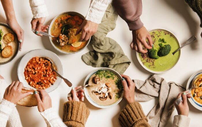A variety of soft and nutritious soups and stews being shared at a communal table, ideal for post-dental surgery recovery.